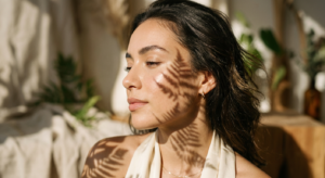 A high-end editorial close-up of a woman’s flawless, glowing skin with soft, warm sunlight casting e