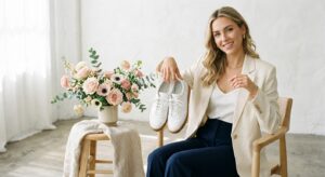 A high-end editorial shot of a stylish woman holding a pair of clean, rejuvenated leather sneakers,